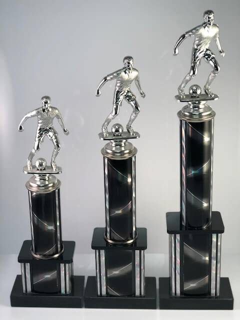 Three sizes of a black soccer trophy with a running soccer player on the top.