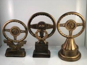 Three trophies with streering wheels made out of metal.
